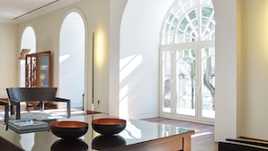 Una habitación amplia con techos altos, ventanas arqueadas y una gran mesa de vidrio.