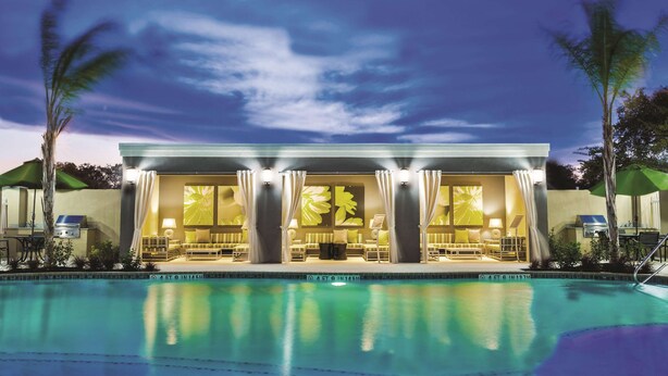 Ein modernes Hotel mit Pool, Sitzgelegenheiten im Freien und Blick auf den Sonnenuntergang.