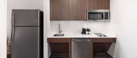 Una cocina compacta equipada con refrigerador, microondas, lavaplatos y pileta.