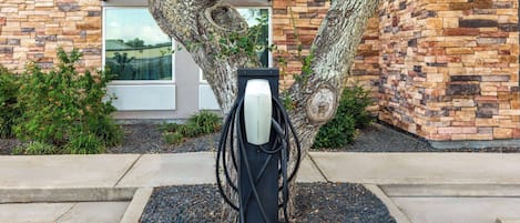 A charging station for electric vehicles in front of a building with stone and brick walls.