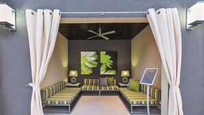 Ein moderner, gut beleuchteter Raum mit einer Sofagarnitur, einem Deckenventilator und Kunstwerken an der Wand.