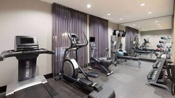 A hotel fitness center with treadmills, elliptical machines, and a stationary bike.