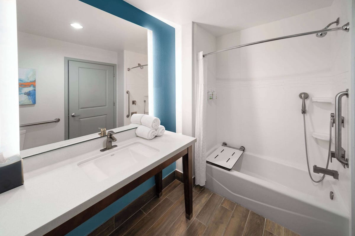Une salle de bain moderne avec un grand miroir, un lavabo et une douche à l’italienne.