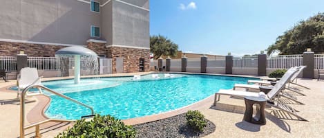A swimming pool with lounge chairs and a stone wall.