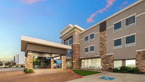Ein mehrstöckiges Hotel mit überdachter Einfahrt, steinernen Details und einem Parkplatz mit Parkplatz für Menschen mit Behinderung.