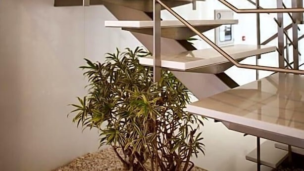 A modern staircase with a geometric design, a small plant, and a pebble-textured floor. - Costa Verde (Povoa De Varzim)