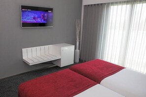 A hotel room with a bed, a TV mounted on the wall, a white cabinet, and a window with curtains. - Costa Verde (Povoa De Varzim)