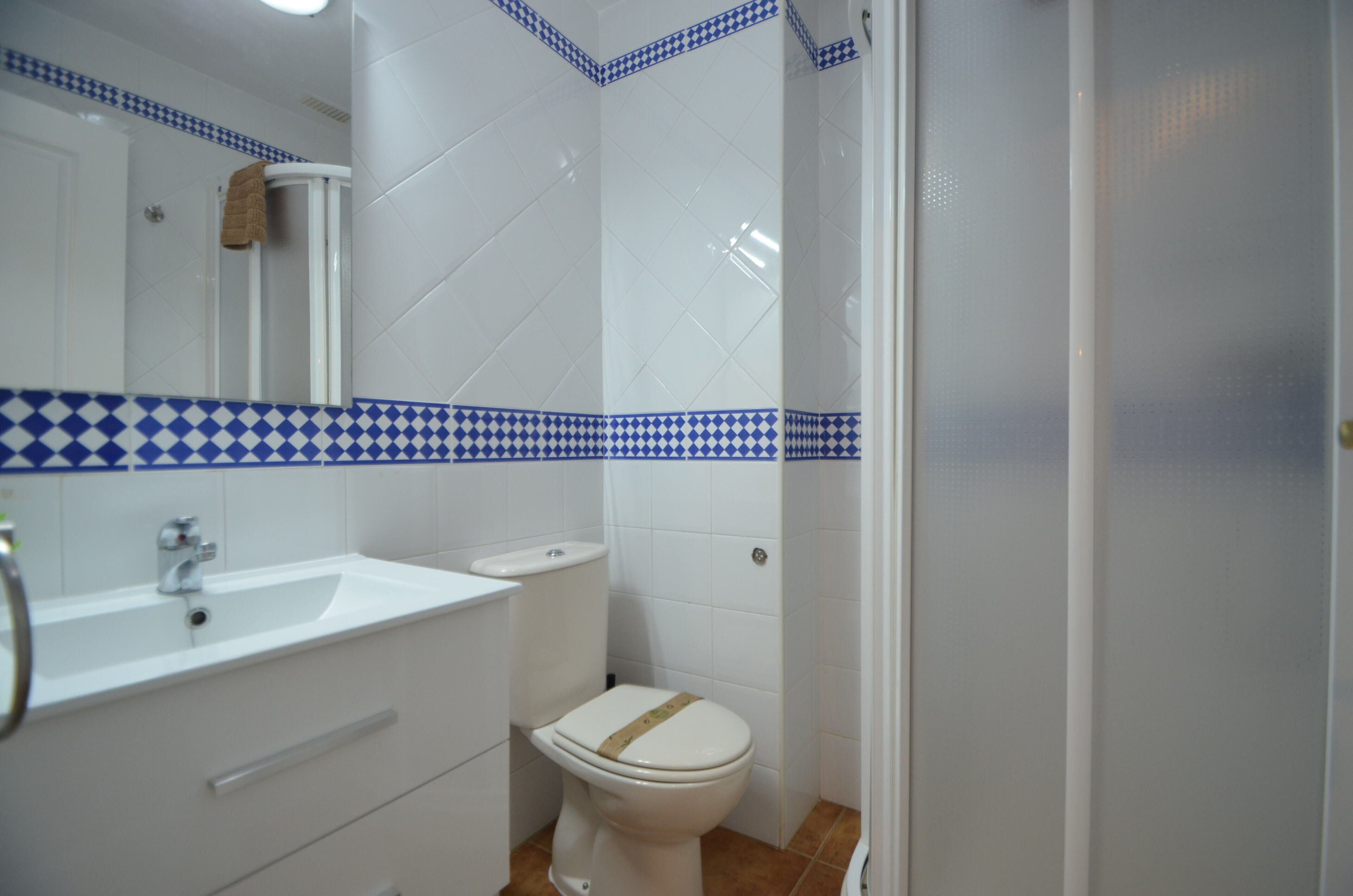 A bathroom with a white sink, toilet, and mirror.