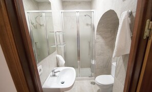 Driepersoonskamer | Badkamer | Een douche, een haardroger, een bidet, handdoeken