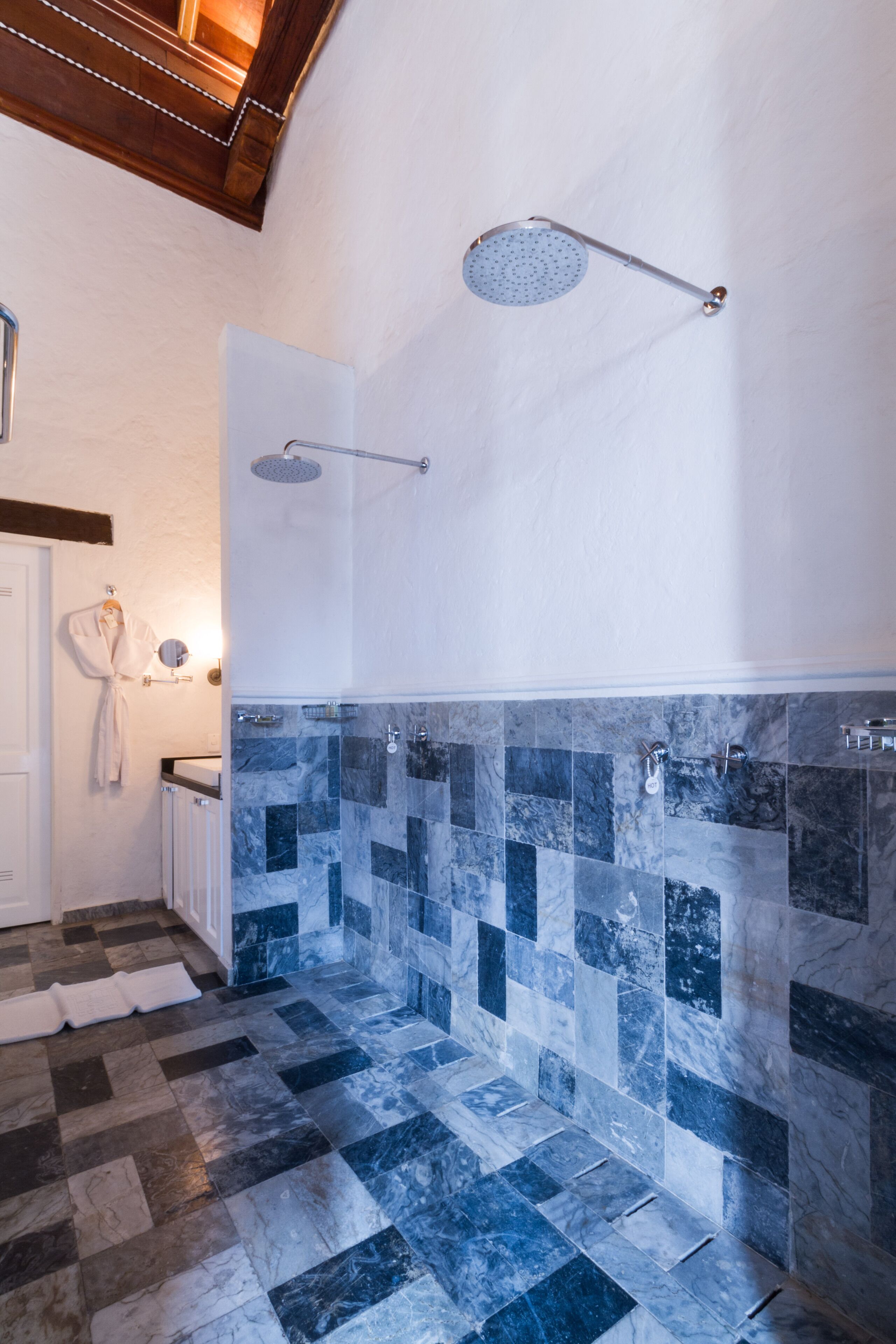 Une salle de bain moderne avec un carrelage à motifs géométriques, une douche équipée d’un pommeau de douche à main et un porte-serviettes avec un peignoir.