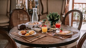 Een ronde houten tafel gedekt met ontbijtartikelen, waaronder croissants, een fruitschaal en een glas sinaasappelsap.