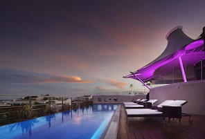 Una piscina al aire libre, sombrillas, sillones reclinables de piscina