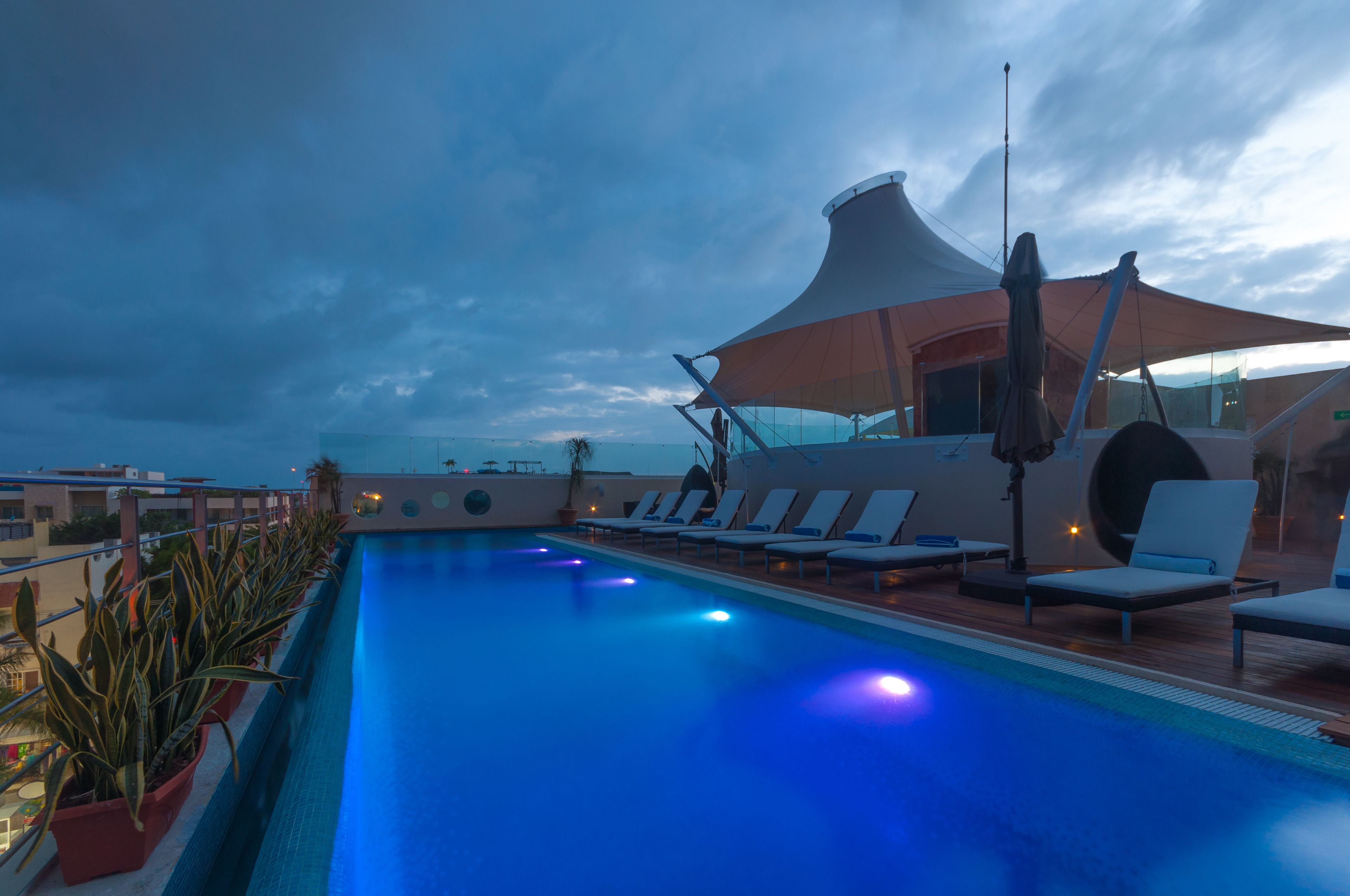 A rooftop pool with lounge chairs and a canopy.