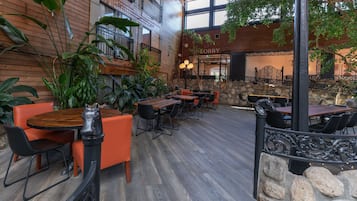 An indoor dining area with wooden walls, stone accents, and multiple tables and chairs.