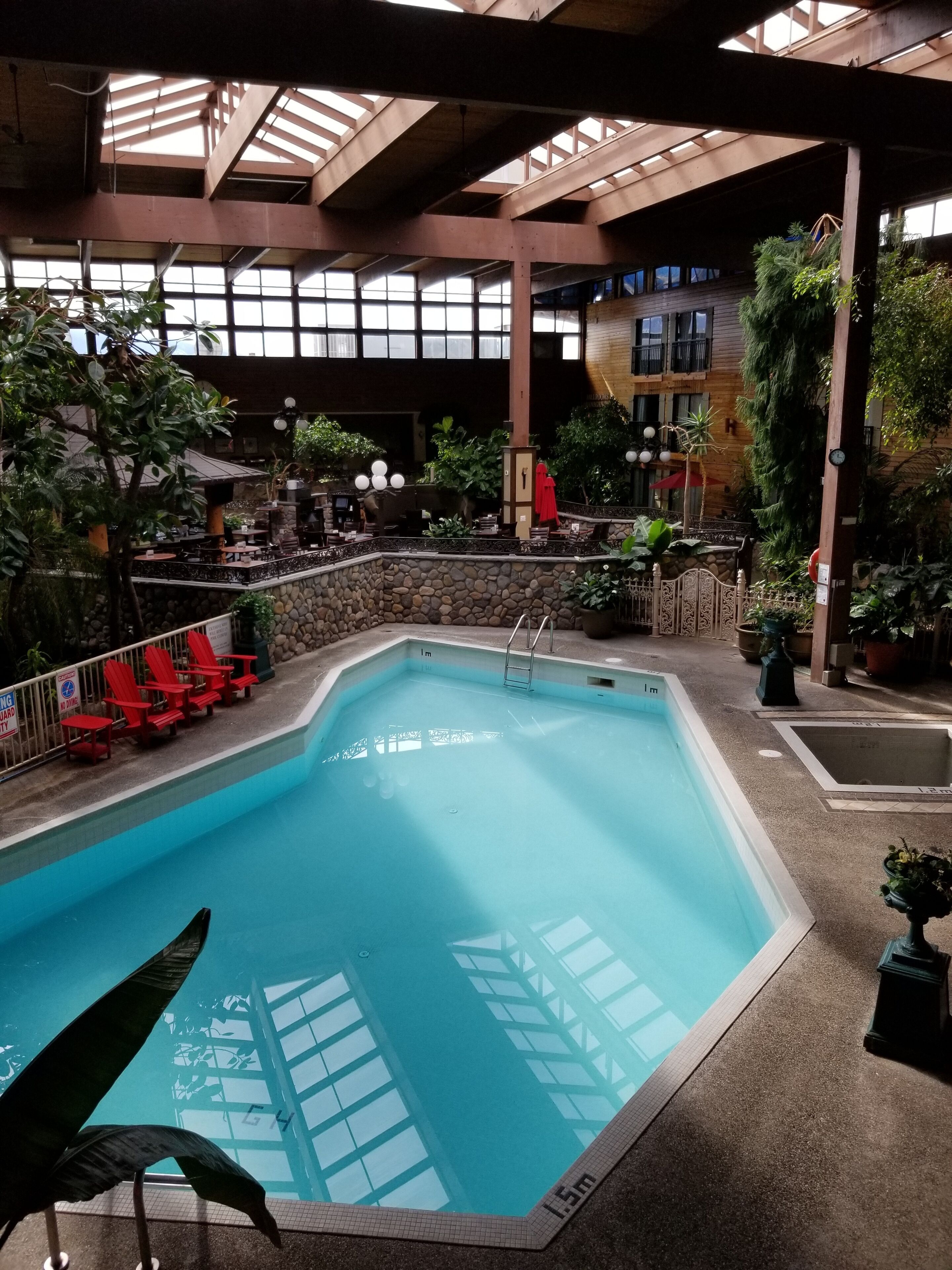 Una piscina interior amb una paret de pedra i cadires vermelles al voltant.