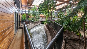 A wooden interior with a water feature, metal railings, and lush greenery. - Prestige Vernon Lodge and Conference Centre (Vernon)