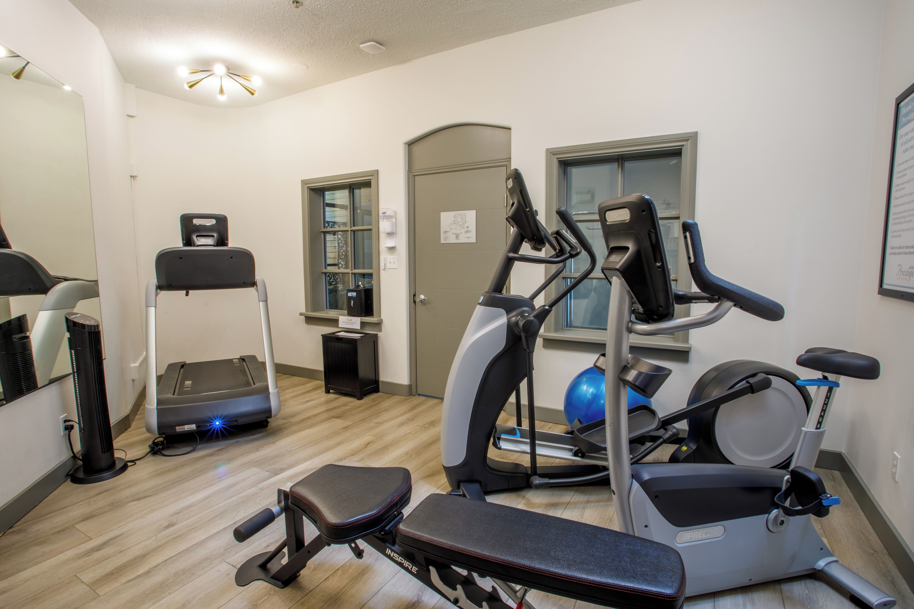 A fitness room with a treadmill, elliptical, and stationary bike.