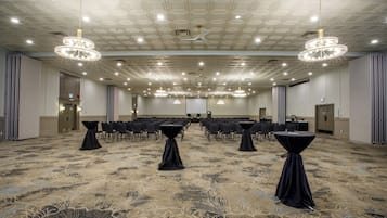 A conference room with a carpeted floor, tables with black tablecloths, and chandeliers.