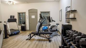 A gym with treadmills, elliptical machines, a stationary bike, and a rack of dumbbells.