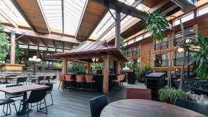 An indoor dining area with wooden tables and chairs, a bar area, and a high ceiling with natural light. - Prestige Vernon Lodge and Conference Centre (Vernon)