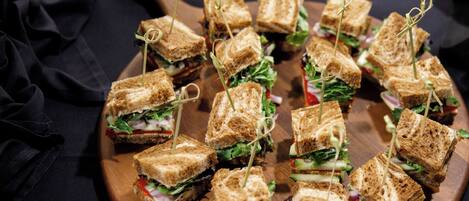 Una tabla de madera con varios sándwiches, cada uno sujeto con palillos.