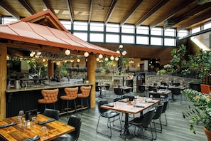 A spacious indoor dining area with high ceilings, wooden beams, and a variety of seating options including bar stools and tables. - Prestige Vernon Lodge and Conference Centre (Vernon)