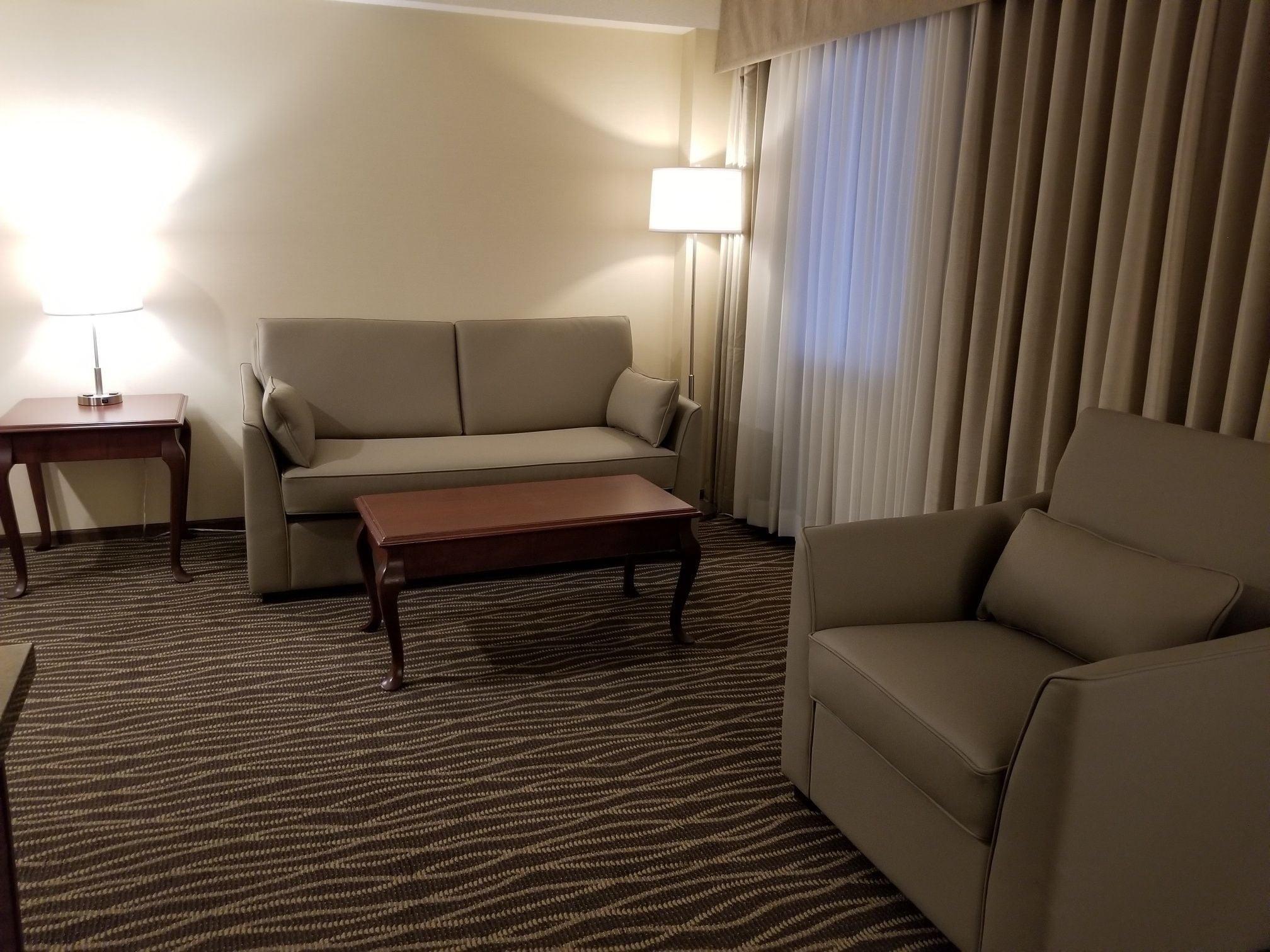 Hotellihuone, jossa on sohva, nojatuoli ja pieni pöytä.