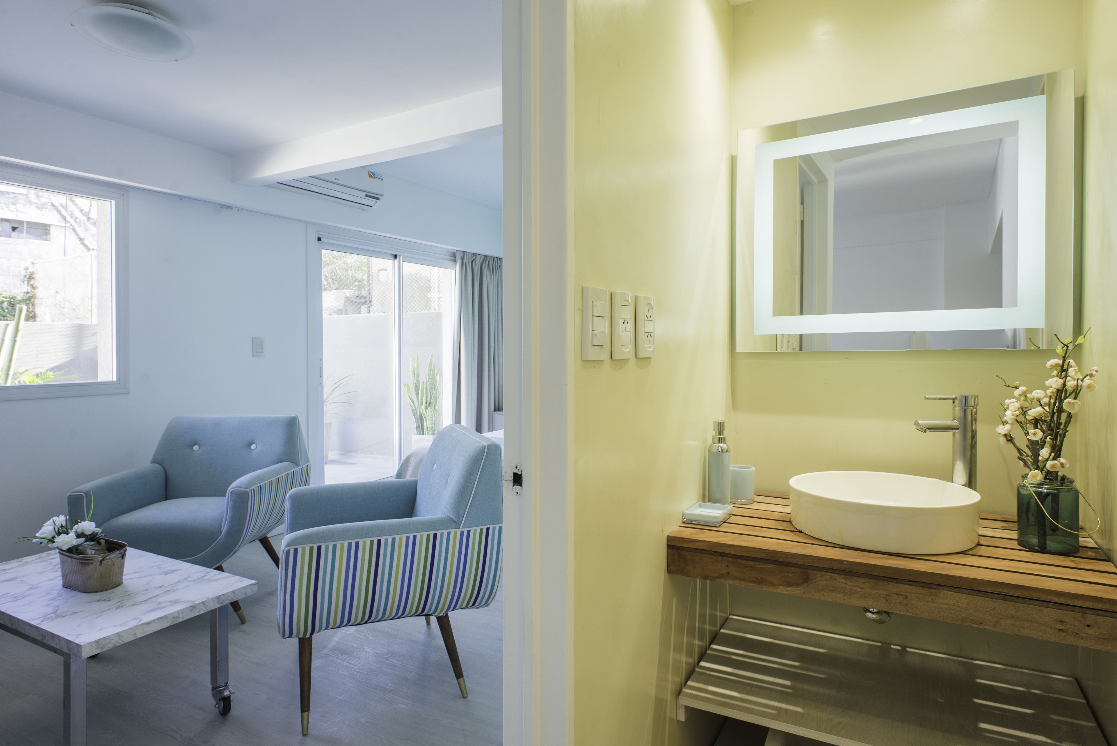 A modern bathroom with a wooden vanity, a large mirror, and a white sink.