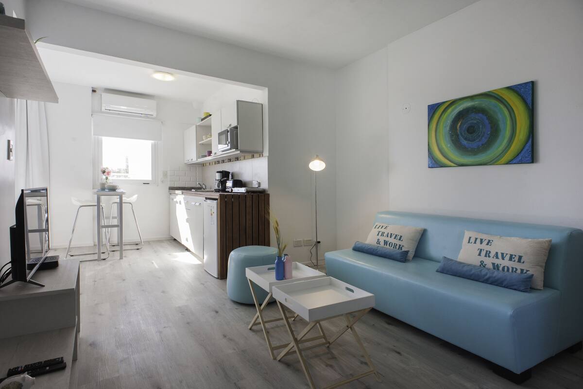 A modern living room with a blue sofa, a coffee table, and a kitchen in the background.
