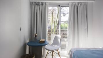 A room with a bed, a small table with a chair, and a window with curtains.