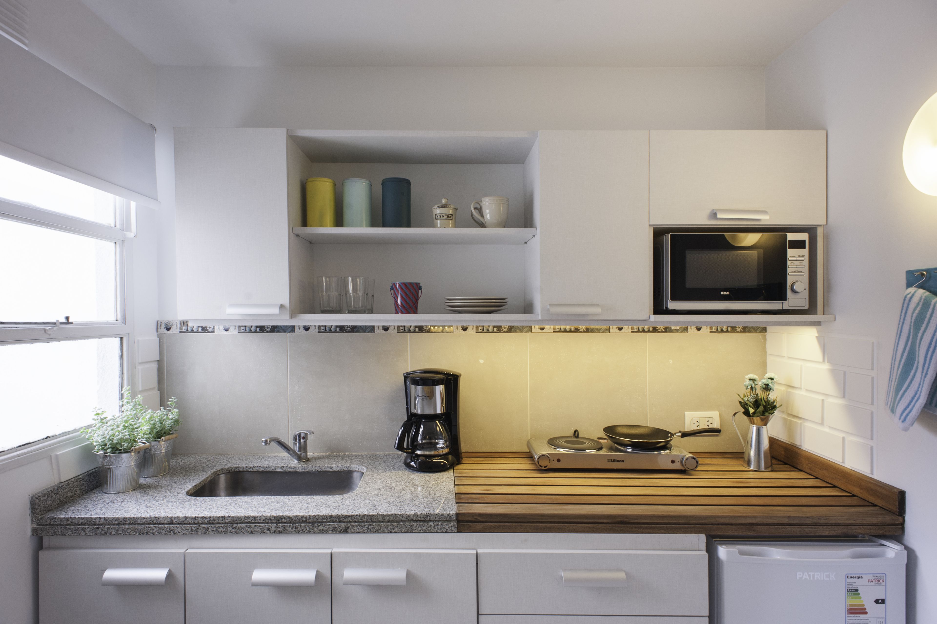 A modern kitchen with a sink, coffee maker, microwave, and wooden countertop.