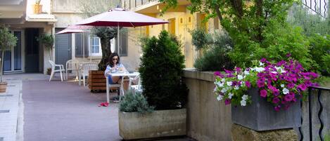 Un patio con mobiliario exterior, una planta en maceta y una cesta de flores colgante.