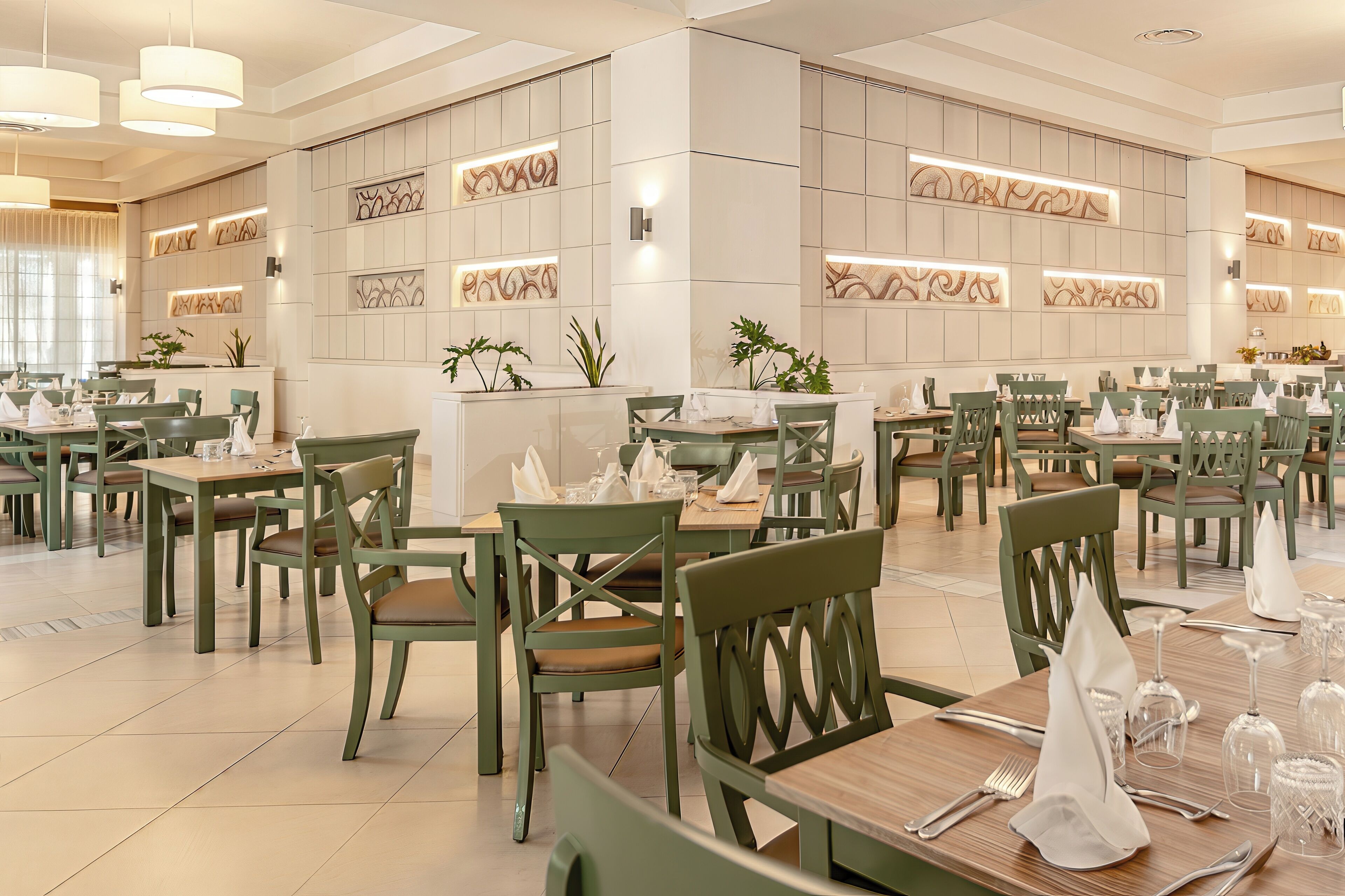Un vaste espace dédié à la restauration, avec de nombreuses tables et chaises, un comptoir d’accueil et des panneaux décoratifs.