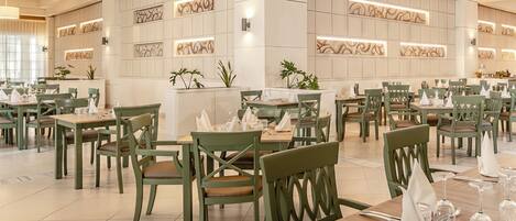 A spacious dining area with multiple tables and chairs, a reception desk, and decorative wall panels.