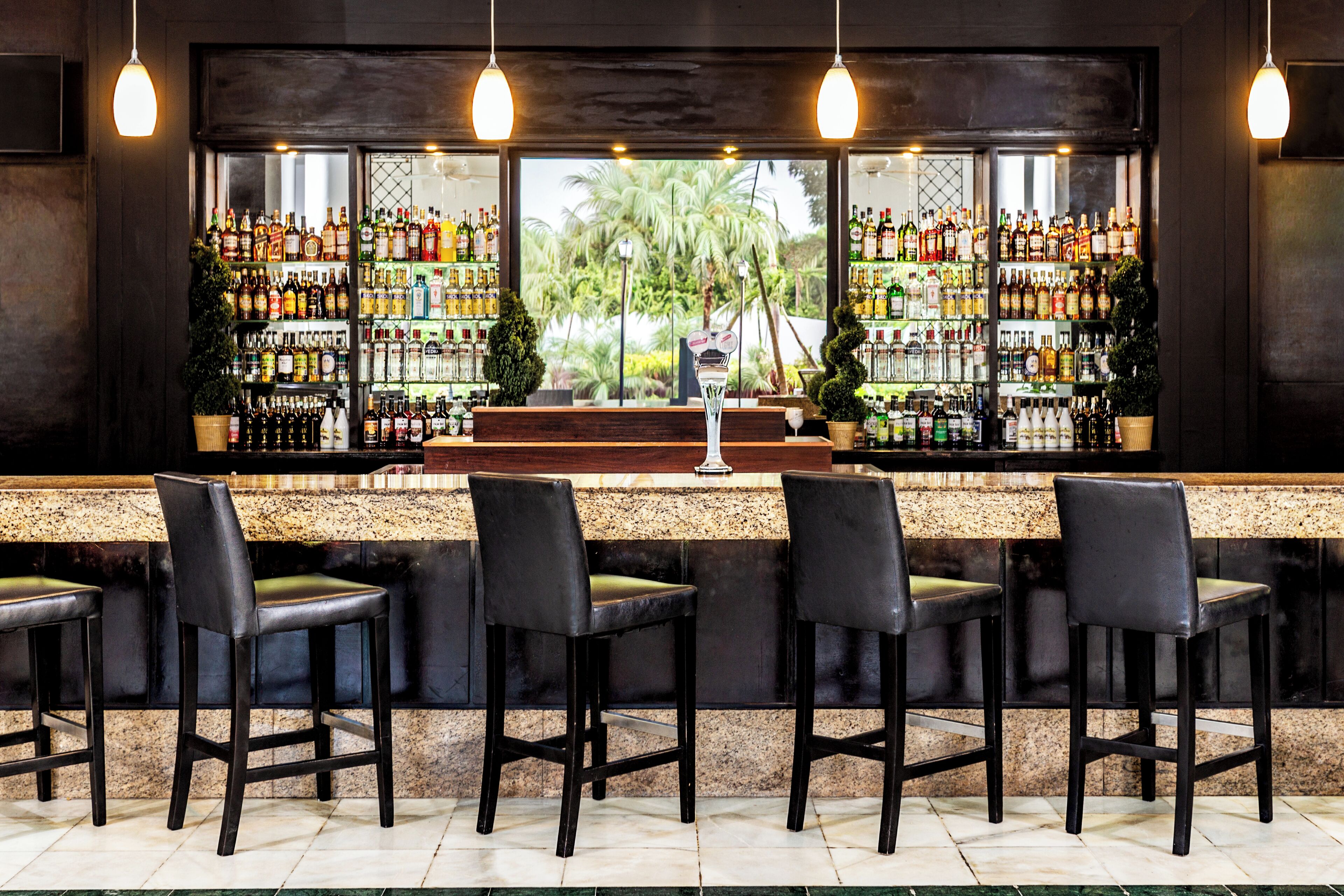 A bar area with a counter, multiple stools, and shelves stocked with bottles.