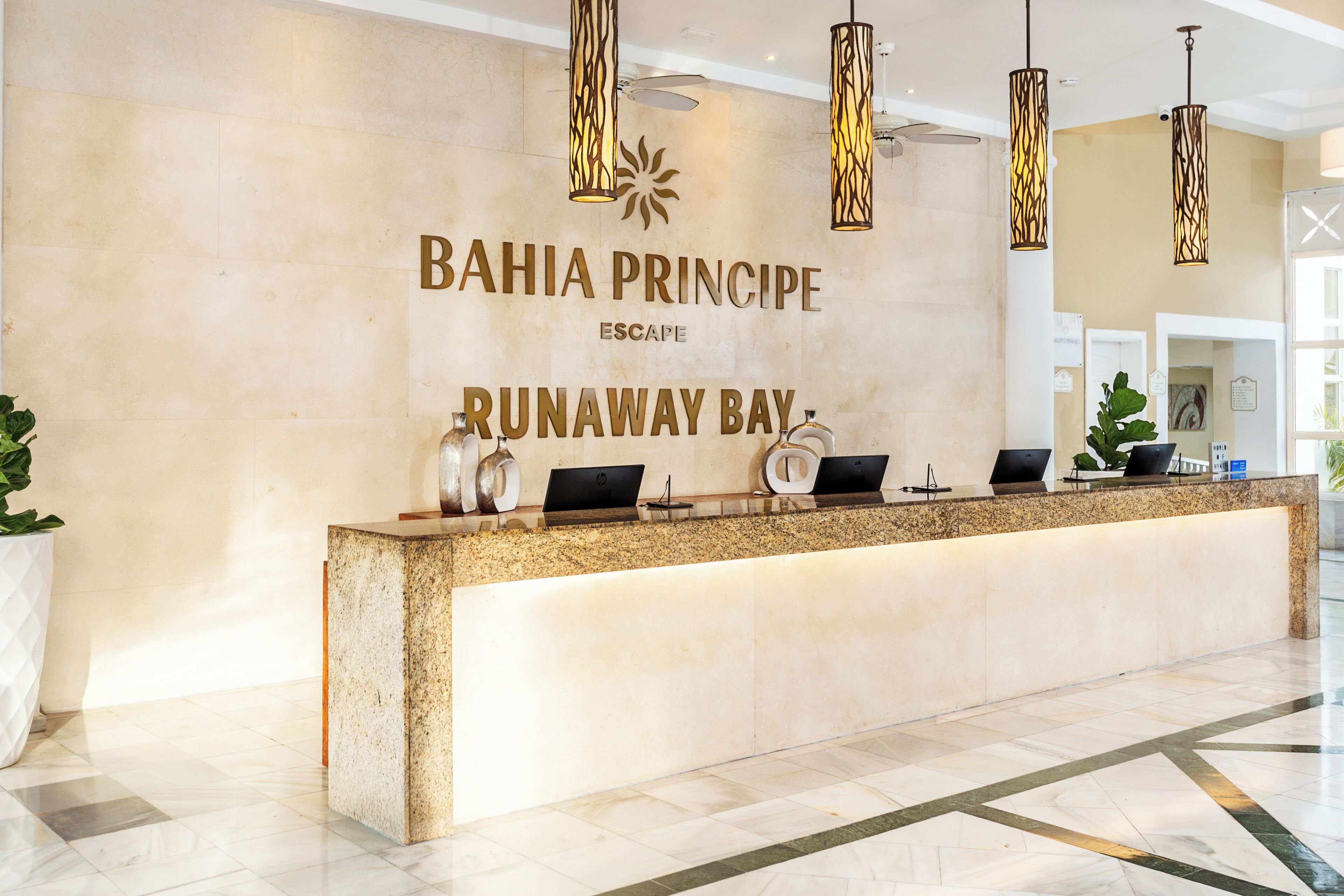 A reception desk with a sign reading 'BAHIA PRINCIPE ESCAPE RUNAWAY BAY.'