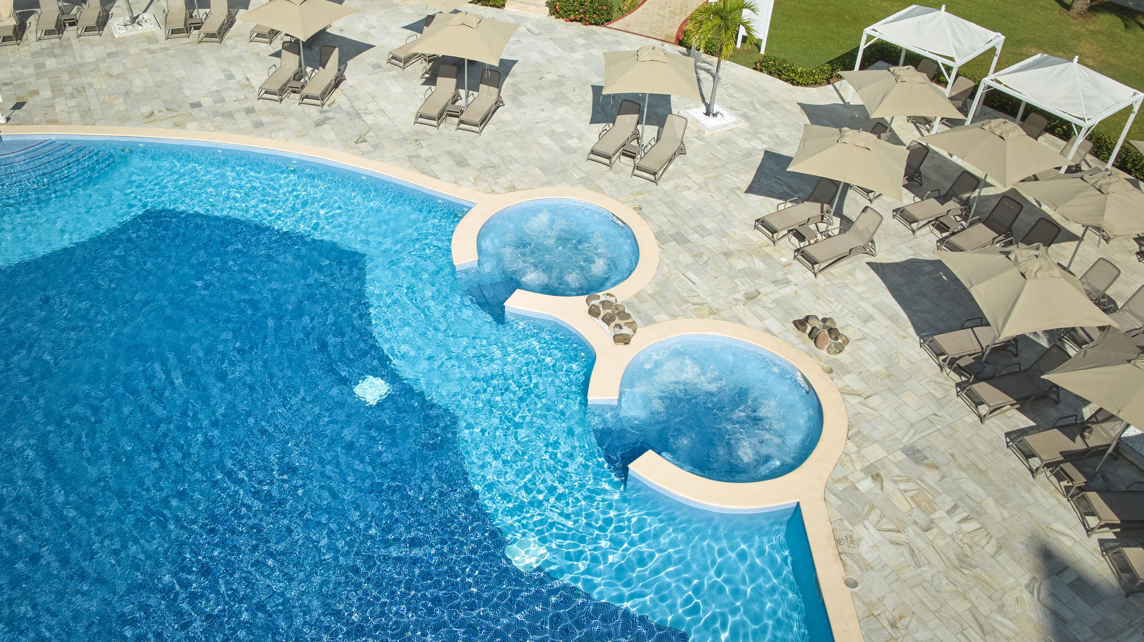 Una gran piscina al aire libre con varias zonas de estar y sombrillas.