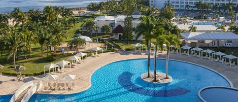 A resort with a large pool, palm trees, and a view of the ocean.
