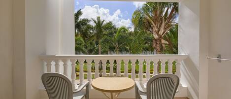 Un balcon avec une balustrade blanche, deux chaises et une petite table ronde.