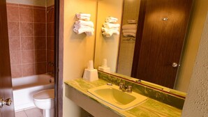 A bathroom with a bathtub, toilet, sink, and a mirror. - Burlington Inn (Burlington)