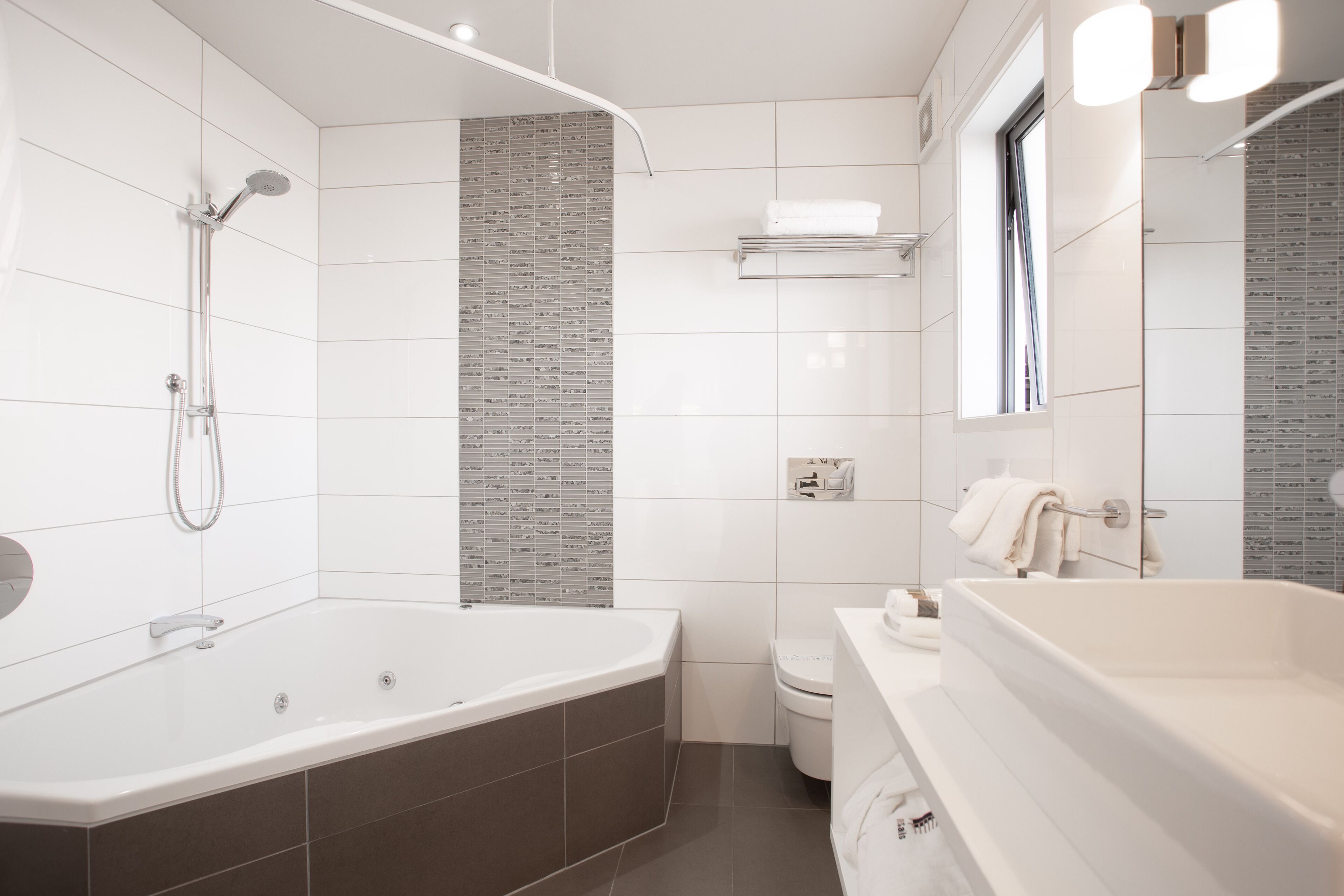 A modern bathroom with a large bathtub, a separate shower area, a toilet, and a sink.