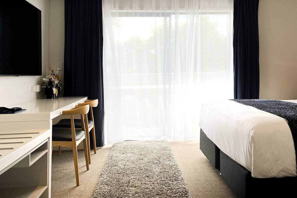 A hotel room with a bed, a desk, and a chair.