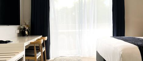 Una habitación de hotel con una cama, un escritorio y una silla.