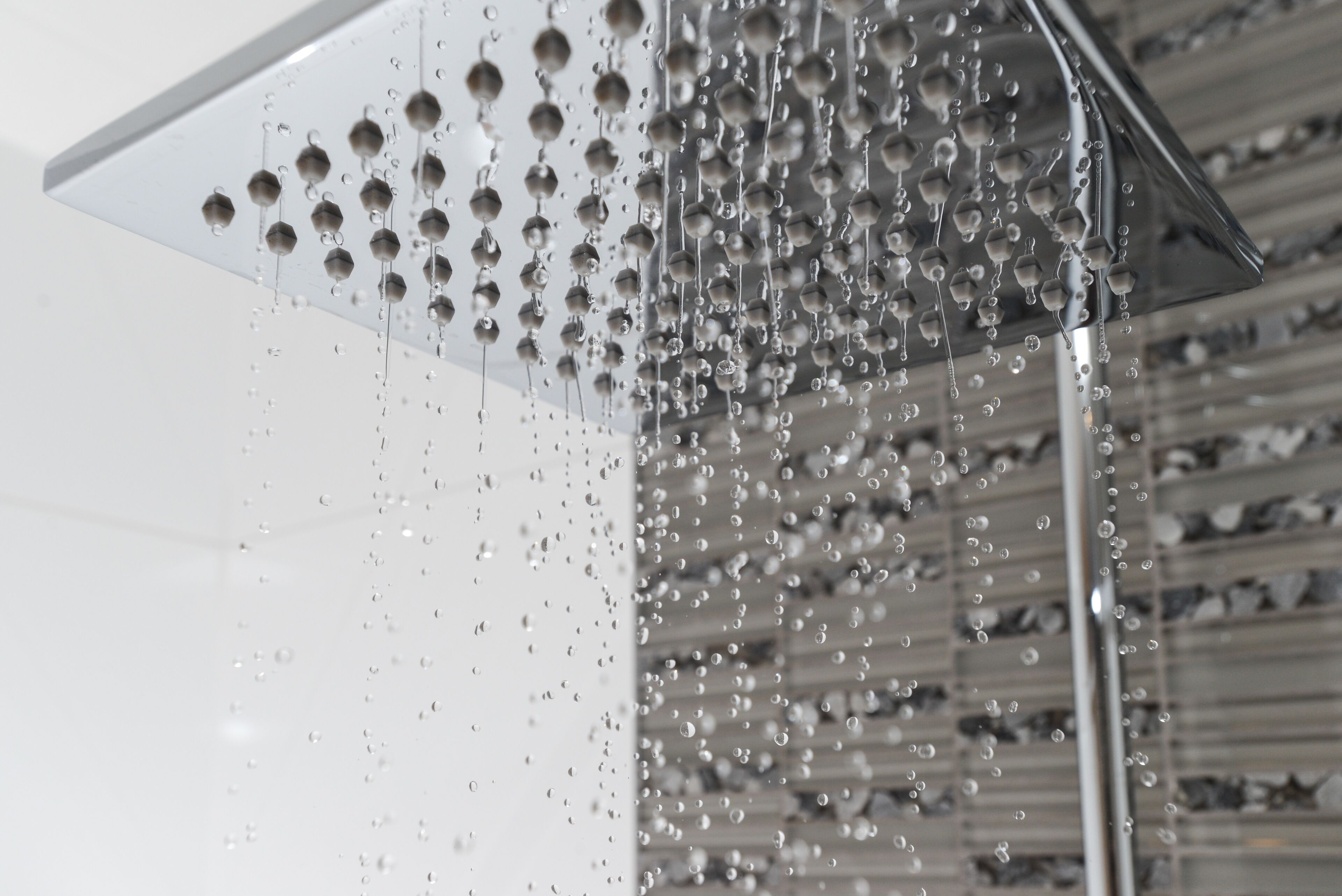 A transparent showerhead with multiple round nozzles, allowing water to flow in a fine mist.