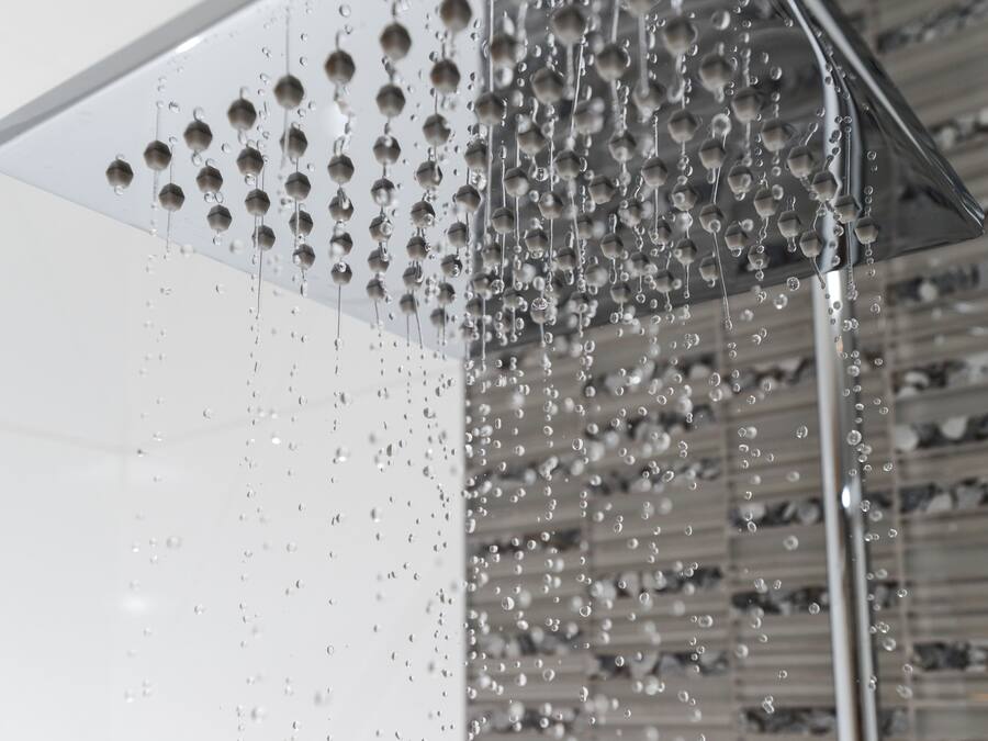 A transparent showerhead with multiple round nozzles, allowing water to flow in a fine mist.