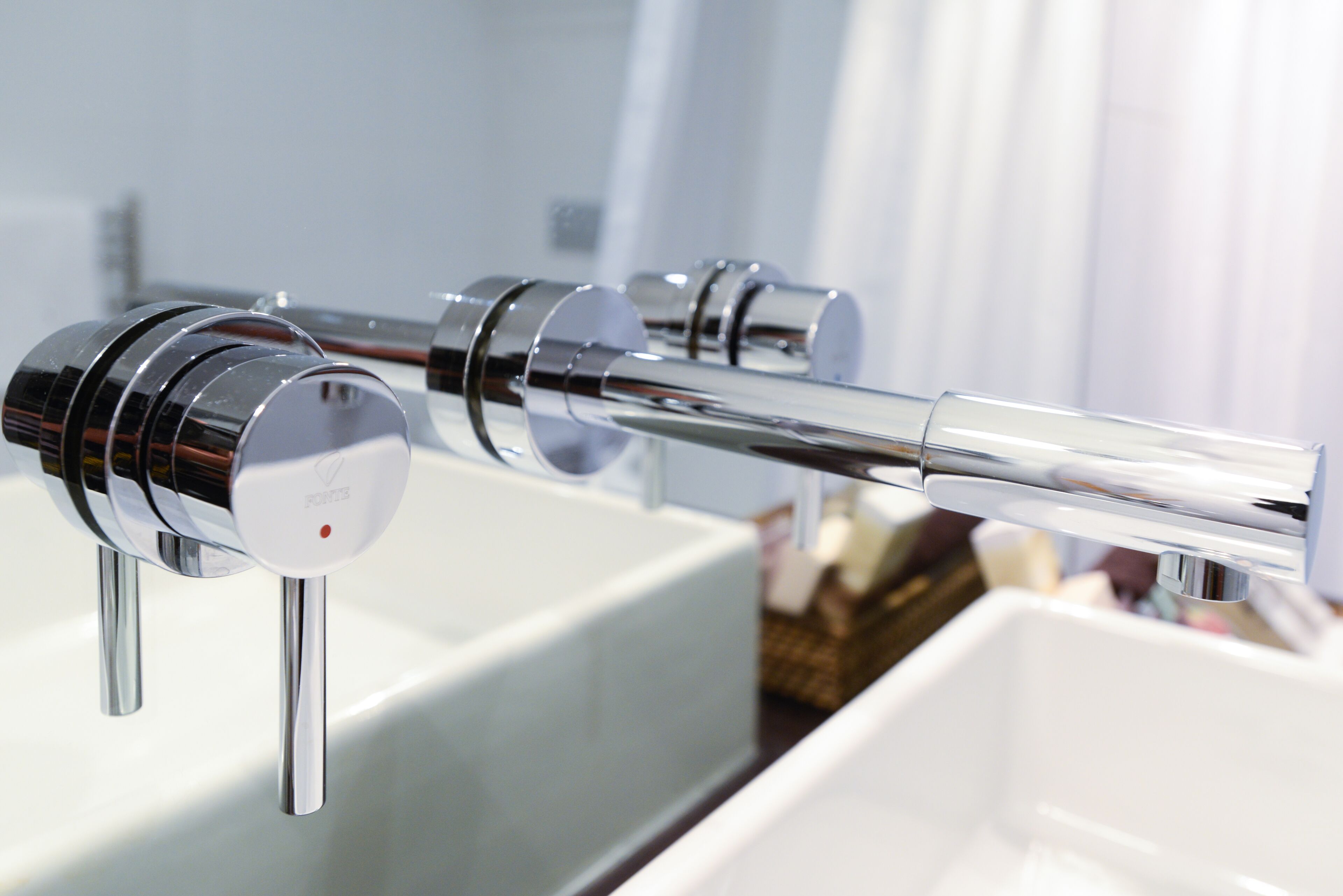 Un grifo cromado de diseño moderno, colocado sobre un lavabo blanco.