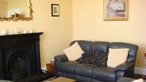 A living room with a dark leather sofa, a small wooden coffee table, and a patterned rug.