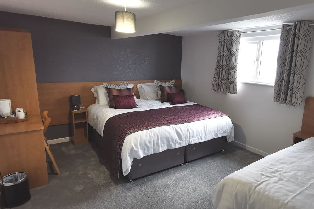 A bedroom with a bed, bedside tables, a desk, and a window with curtains.