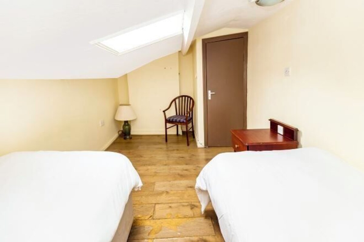 A room with two beds, a chair, a lamp, and a door.