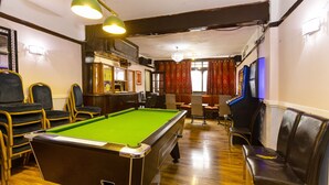 A pool table in a room with wooden flooring, chairs, and a bar area. - Old Oak Tree Inn (Southall)